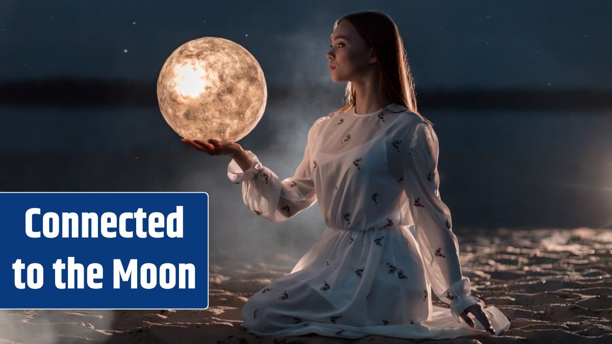 Beautiful young attractive girl on a night beach with sand and stars holds the moon in her hands.